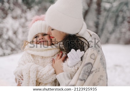 Mom and daughter in a snowy forest. Christmas theme, mom and daughter in white clothes.