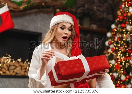 Girl in Santa's hat opening Christmas gift