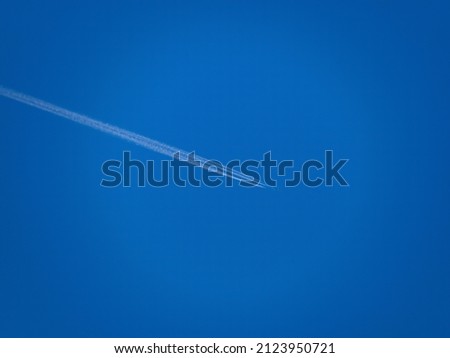 Beautiful picture of white plane flying with trail in blue sky..