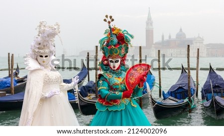 Beautiful costume of womans in green and white colours in Venice, there is a sea, gondollas and basilica San Giorgio Maggiore at the background, fog weather