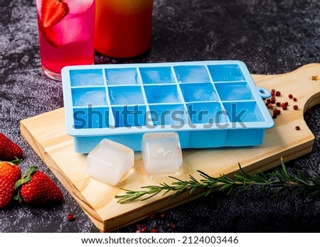 Blue silicone ice cube tray on table with fruit and strawberry drink Royalty-Free Stock Photo #2124003446