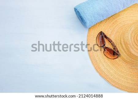 Summer hat, sun glasses and a towel on a blue wooden background. The concept of summer, the sea and recreation, freedom.