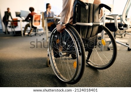 Rear view of businesswoman with disability uses wheelchair while going through the office. Royalty-Free Stock Photo #2124018401