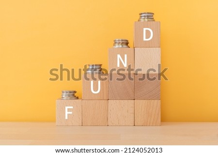 Wooden blocks with "FUND" text of concept and coins.