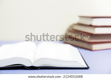 Composition with piggy bank and hardback books, diary, fanned pages on wooden deck table and colored background. Books stacking. Back to school. Copy Space. Education background.