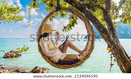Traveler woman relaxing on straw nests using tablet at Railay beach Krabi, Asia business people on vacation at resort work with computer notebook, Tourist travel Phuket Thailand summer holiday trip Royalty-Free Stock Photo #2124096590