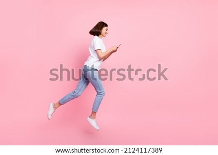 Full size profile side photo of pretty girl casual wear jumping walking chatting on phone isolated on pink color background