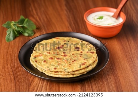 Palak paratha butter on spinach paratha , parantha ,chapati Indian flatbread roti made from spinach served in golden plate with yogurt mint dip, mango pickle, North Indian breakfast food Delhi India. Royalty-Free Stock Photo #2124123395