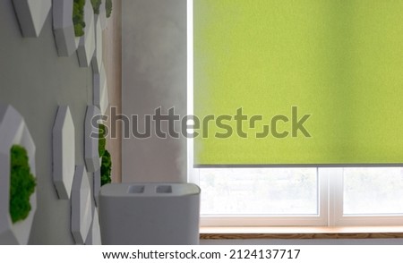 Roller blinds closeup on the window in the interior. Roller shades for big windows. Automated curtains for office. Green color, monochrome material. Window coverings. Royalty-Free Stock Photo #2124137717