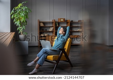 Wellbeing for self-employed freelance workers. Happy smiling female freelancer with laptop on knees relaxing with hands behind head and closed eyes, remote employee feeling satisfied with work done Royalty-Free Stock Photo #2124144707