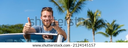 Car key new young owner driver man showing keys and thumbs up happy for new convertible buy or sell used cars. Driver's license concept with driving cabriolet on road trip banner panoramic. Royalty-Free Stock Photo #2124145157