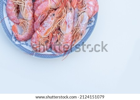 Red boiled king prawns unpeeled on a blue plate, top view