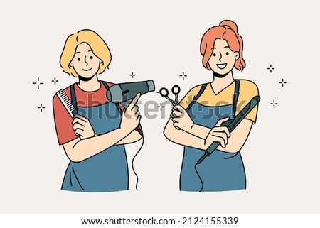Working as hairdresser in salon concept. Two young smiling girls wearing aprons standing holding working tools in hairdressing salon vector illustration  Royalty-Free Stock Photo #2124155339