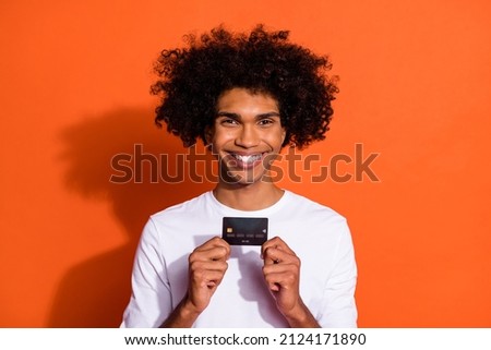 Photo of funny pretty guy wear white shirt smiling buying bank card isolated orange color background