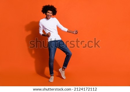 Photo of sweet charming guy wear white shirt dancing smiling empty space isolated orange color background