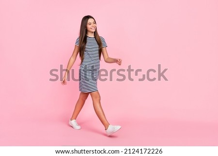 Photo of cute dreamy girl dressed striped dress walking looking empty space isolated pink color background