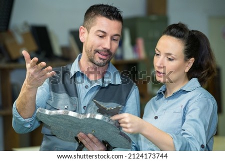 workers holding and discussing ornamental memorial plaque Royalty-Free Stock Photo #2124173744