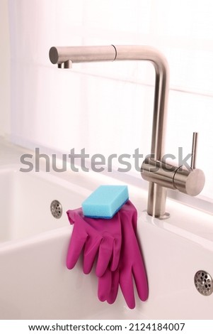 Sponge and rubber gloves on kitchen sink indoors