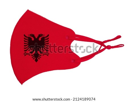 Red cotton reusable cloth protective mask looks as flag of Republic of Albania isolated on white background.
