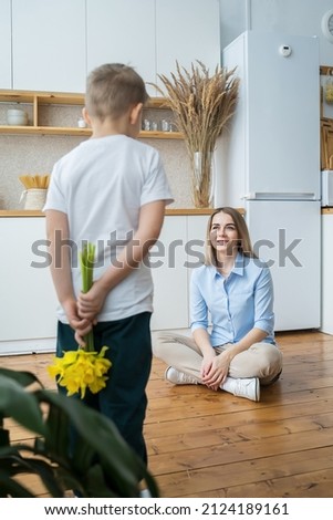 vertical image. happy mother's day! little son gives flowers to mom, boy congratulates mom, flowers in the hands of a boy, yellow daffodils, happy mom and little son. 8 march
