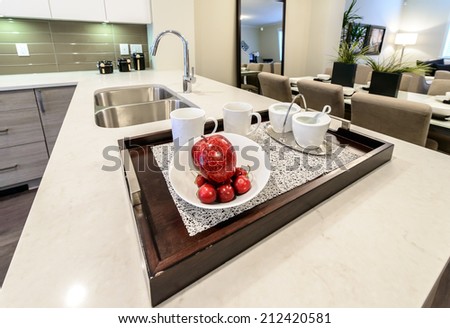 Kitchen counter with the tray with coffee, tea set and some fruits, apples on it. Interior design.