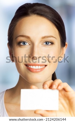 Closeup portrait of smiling businesswoman showing mockup empty businesscard or plastic credit card with copy space blurred office background. Brunette business woman at studio image. dental ad concept
