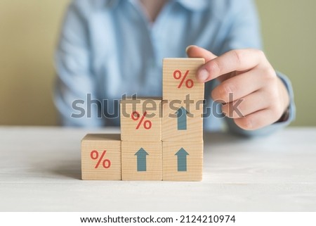 Interest rate financial and mortgage rates concept. Hand putting wood cube block increasing on top with icon percentage symbol and arrow upward direction Royalty-Free Stock Photo #2124210974