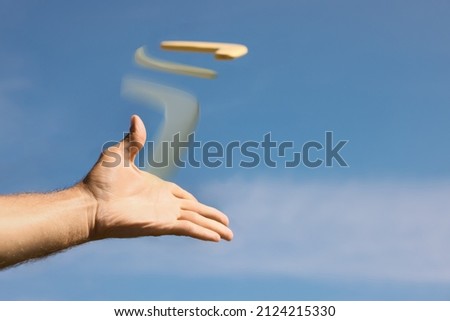 Man throwing boomerang against blue sky, closeup Royalty-Free Stock Photo #2124215330