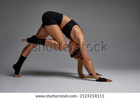 Animal instinct fitness female instructor showing his incredible flexibility with an animal flow move in studio against a gray background