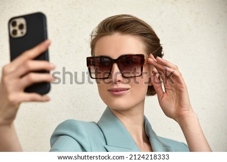 Close-up of trendy girl face in sunglasses is making selfie photo.