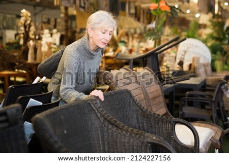 Portrait of senior woman looking for comfortable plastic rattan garden furniture in furnishings store..