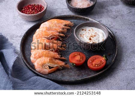 Cooked prawns, plate with boiled shrimps, sauce and spices on a gray background.