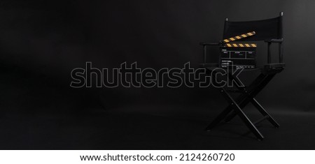 Black director chair. Yellow and black color Clapper board or movie slate on a chair with a black background.