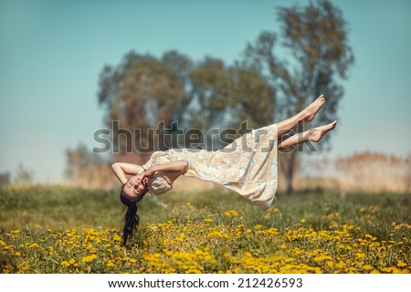 Girl floating in weightlessness over the meadow of dandelions. Royalty-Free Stock Photo #212426593