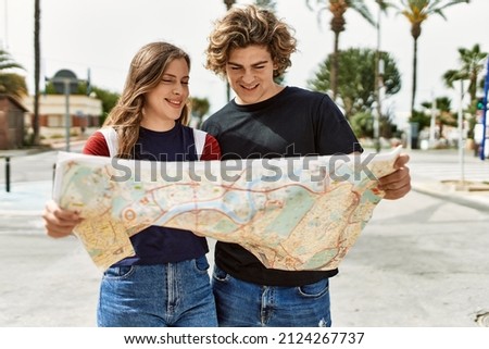 Young caucasian tourist couple smiling happy looking city map standing at the street.