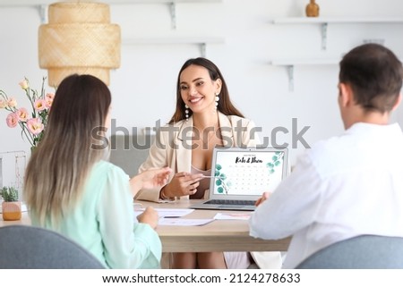 Female wedding planner discussing ceremony with clients in office Royalty-Free Stock Photo #2124278633