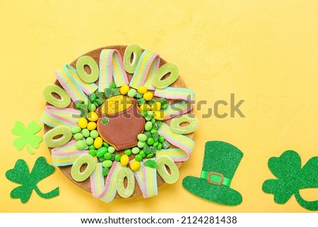 Plate with different sweets for St. Patrick's Day celebration on yellow background