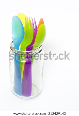 Colorful plastic spoons and forks in jar .