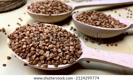 Buckwheat tea in a wooden spoon on a light wooden background. Buckwheat tea close-up macro photography. Scattered buckwheat tea pellets on wooden background