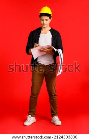 Vertical close up shot of Asian handsome male model posing for a photographer by happy mood in architect theme isolated on red background.