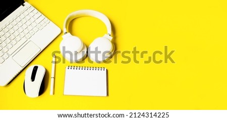 On an isolated yellow background, a flat lay, a paper notepad for writing on a spiral, a computer mouse, headphones, a pen.  Online training concept, webinar.Baner with copy space for text.