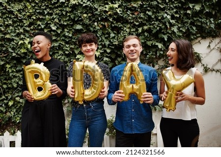 Cropped portrait of a group of friends holding up ballon letters reading BDAY while celebrating a birthday outdoors