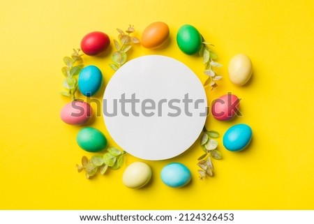 round frame multicolored Easter eggs with white blank paper on a brown background, close-up, space for text, blank for design, selective focus, tinted image.