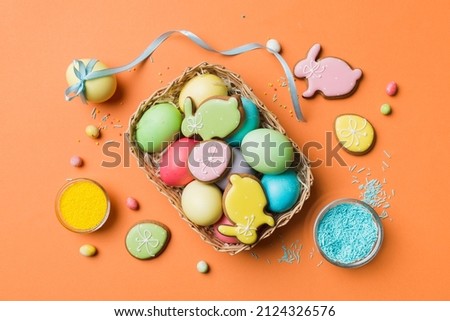 Colorful easter cookies in basket with Multi colors Easter eggs on colored background . Pastel color Easter eggs. holiday concept with copy space.