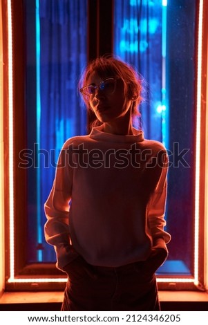 Futuristic style portrait woman wearing eyeglasses in blue and purple neon light. modern glow night city