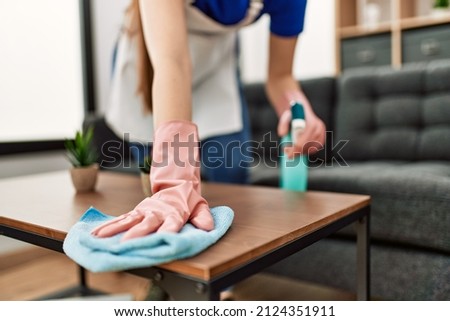 Woman cleaning table using rag and diffuser at home. Royalty-Free Stock Photo #2124351911