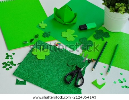 St. Patrick's Day DIY concept. Top view of a table with green sheets of paper, glitter, pencils, scissors, shamroks.
