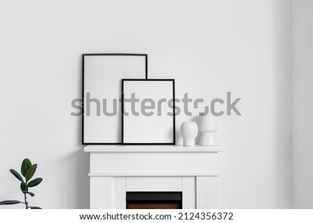 Fireplace with blank poster frames in light bedroom
