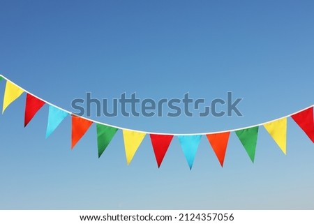 Bunting with colorful triangular flags against blue sky Royalty-Free Stock Photo #2124357056