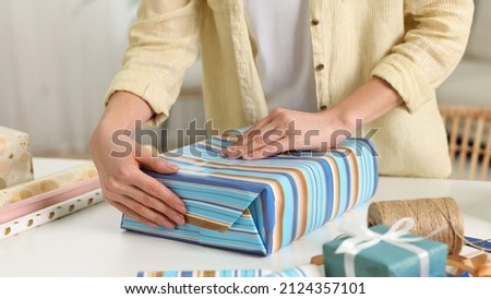 Woman wrapping gift at white table indoors, closeup Royalty-Free Stock Photo #2124357101